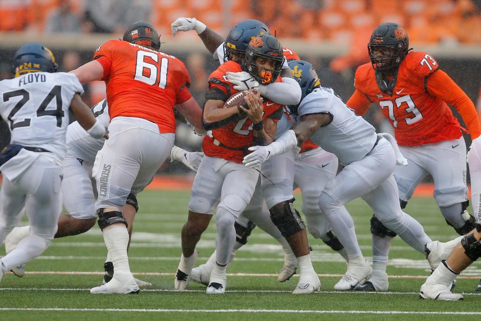 Oklahoma State Cowboys running back Ollie Gordon (0) is brought down by West Virginia Mountaineers defensive lineman Jordan Jefferson (95) during a college football game between Oklahoma State and West Virginia at Boone Pickens Stadium in Stillwater, Okla., Saturday, Nov. 26, 2022. West Virginia won 24-19. 