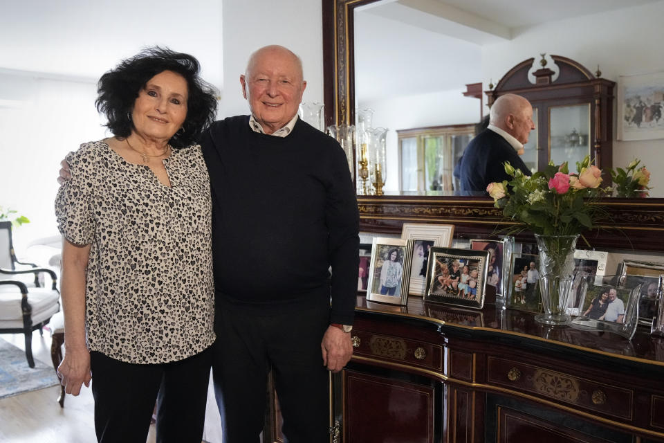 Holocaust survivor Herbert Rubinstein and his wife Ruth stand beside photos of their family after an interview with The Associated Press at their home in Duesseldorf, Germany, Thursday, April 25, 2024. Holocaust survivors from around the globe participating in a new digital campaign called "#CancelHate" which features videos of them reading Holocaust denial posts from different social media platforms. (AP Photo/Martin Meissner)