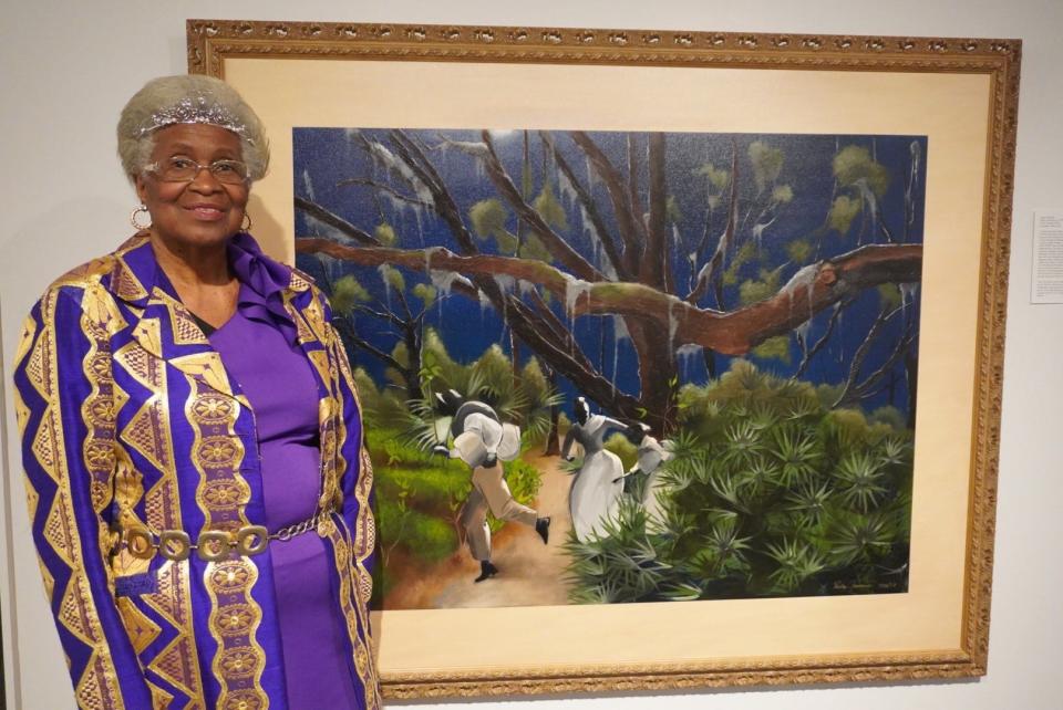 Lizzie Jenkins, CEO and founder of the Real Rosewood Foundation Inc, stands next to the painting titled “Rosewood: Hope Prevails” by artist Pedro Jermaine on display at the "An Elegy to Rosewood" exhibit at the Gainesville Fine Arts Association through March 23.
(Credit: Photo by Voleer Thomas, Correspondent)