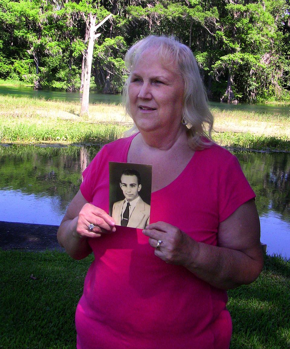 Sylvia Sauls Waugh in the backyard of her home in Dunnellon, near Ocala. She was born in March 1943. She's holding a photograph of her father, Bert Sauls, Jr., master gunner of The Fourteen, who died when she was an infant.