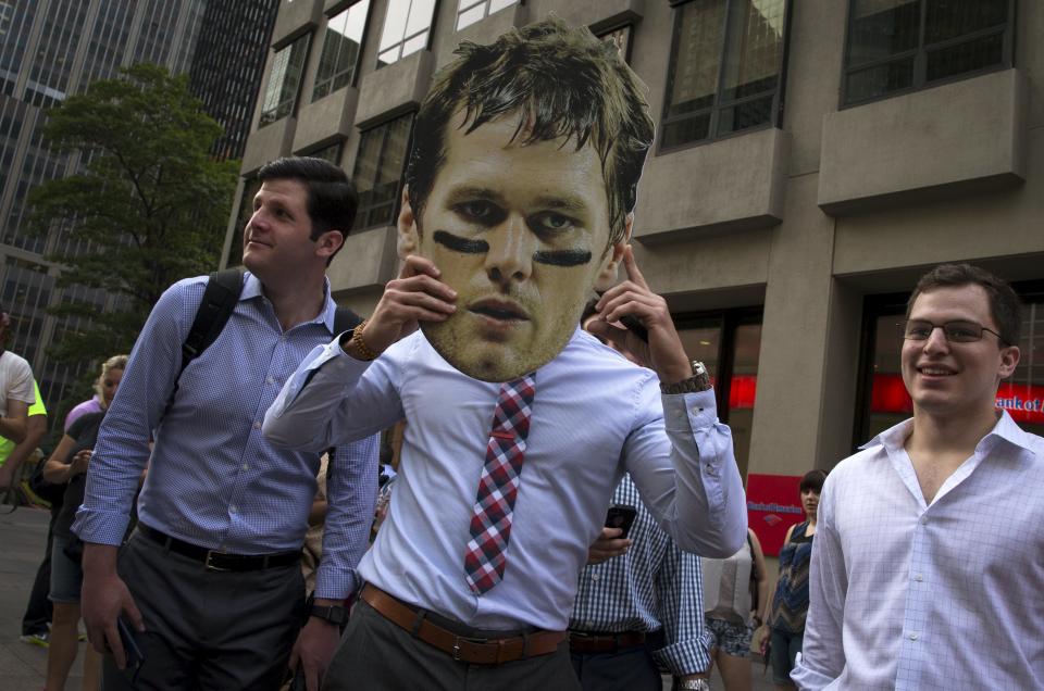 A man holds a picture of New England Patriots quarterback Tom Brady over his face outside the National Football League (NFL) headquarters offices in the Manhattan borough of New York City, June 23, 2015. Brady's appeal of his four-game NFL suspension for participating in a scheme to deflate footballs during last season's playoffs begins Tuesday at NFL headquarters in New York. REUTERS/Mike Segar