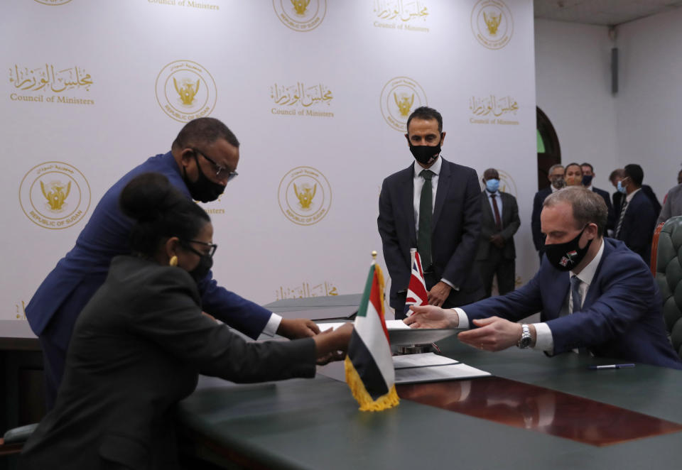 Sudanese Finance Minister Heba Mohamed Ali, left, and British Foreign Secretary, Dominic Raab sign copies of a Memorandum of Understanding, in the Cabinet Building, in Khartoum, Sudan, Thursday, Jan. 21, 2021. Raab was in the Sudanese capital Thursday to discuss bilateral relations and tensions along the border with Ethiopia, Sudan's state news agency reported. (AP Photo)