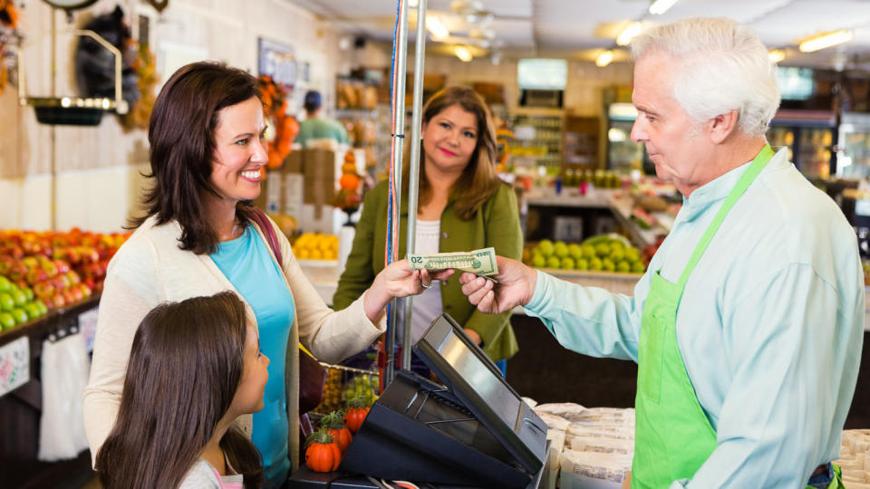 woman handing cash to older cashier