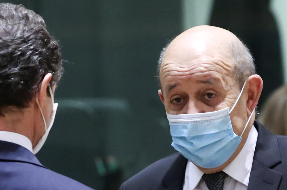 French Foreign Minister Jean-Yves Le Drian speaks with an official during a meeting of EU foreign ministers at the European Council building in Brussels, Monday, Feb 22, 2021. European Union foreign ministers on Monday will look at options for imposing fresh sanctions against Russia over the jailing of opposition leader Alexei Navalny as the 27-nation bloc considers the future of its troubled ties with the country. (Yves Herman, Pool via AP)