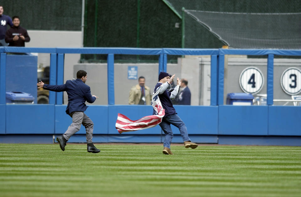 A security guard chases down a fan who ran onto the field with an American flag tied around him during the seven inning strech of the game between the New York Yankees and the Minnesota Twins at Yankee Stadium on April 10, 2003 in the Bronx, New York. The Yankees defeated Twins 2-0. (Photo by Ezra Shaw/Getty Images)