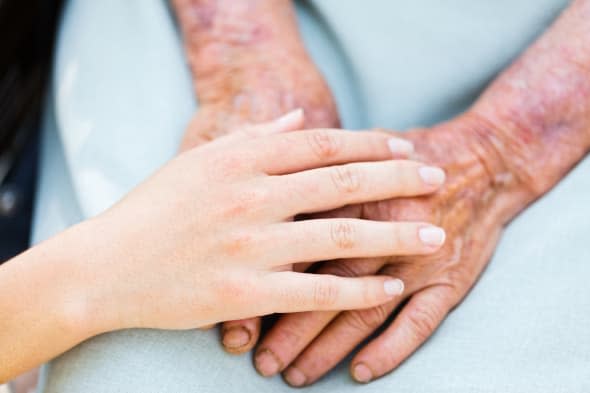 Caring woman hands over elderly hands being concept of trust and reliability.