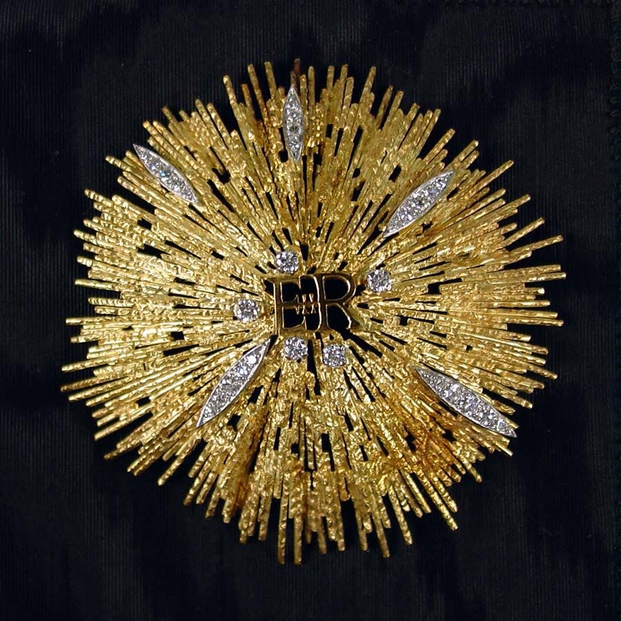 Gold brooch given to First Lady Betty Ford by Queen Elizabeth II during American Bicentennial celebrations. The custom designed star burst brooch by Grima features the Queen’s cipher “ER” at center, accented by five scattered diamonds and five marquise-shaped panels of diamonds, and a Royal stamp on the back.                               