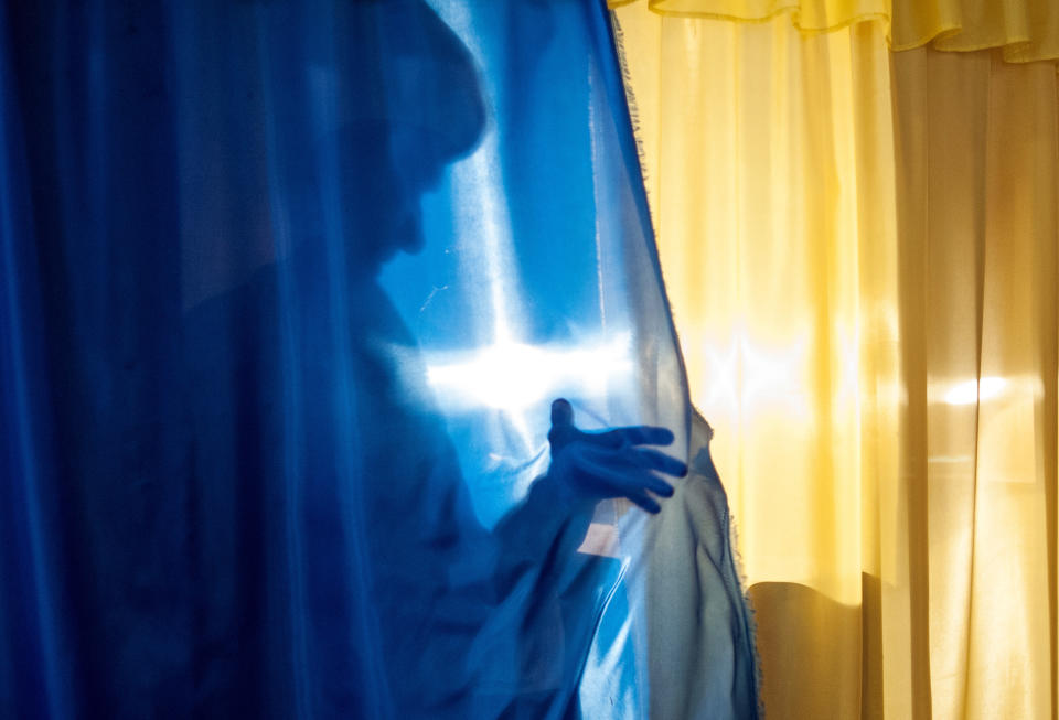 A local resident casts a shadow leaving a booth to cast her ballot at a polling station in Luhansk, Ukraine, on Sunday, May 11, 2014. Residents of two restive regions in eastern Ukraine cast ballots Sunday in referendums, which seek approval for declaring sovereign people's republics in the Donetsk and Luhansk regions. (AP Photo/Evgeniy Maloletka)