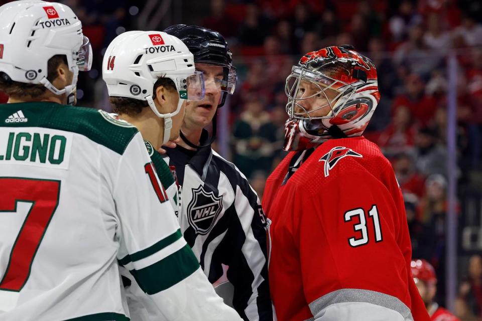 An official steps between Minnesota Wild’s Joel Eriksson Ek (14) and Carolina Hurricanes goaltender Frederik Andersen (31) with Wild’s Marcus Foligno (17) nearby during the third period of an NHL hockey game in Raleigh, N.C., Thursday, Jan. 19, 2023. (AP Photo/Karl B DeBlaker)