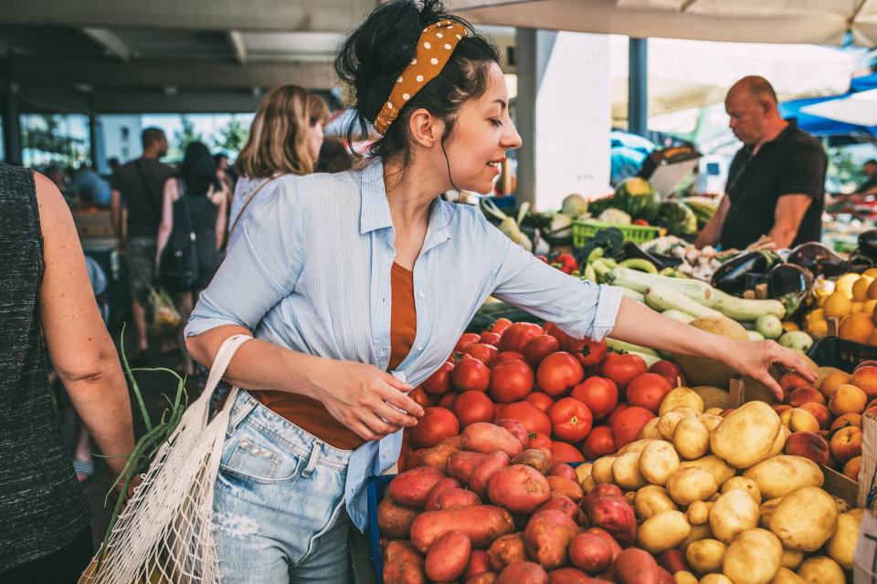 A woman selects fruits and vegetables at a market
