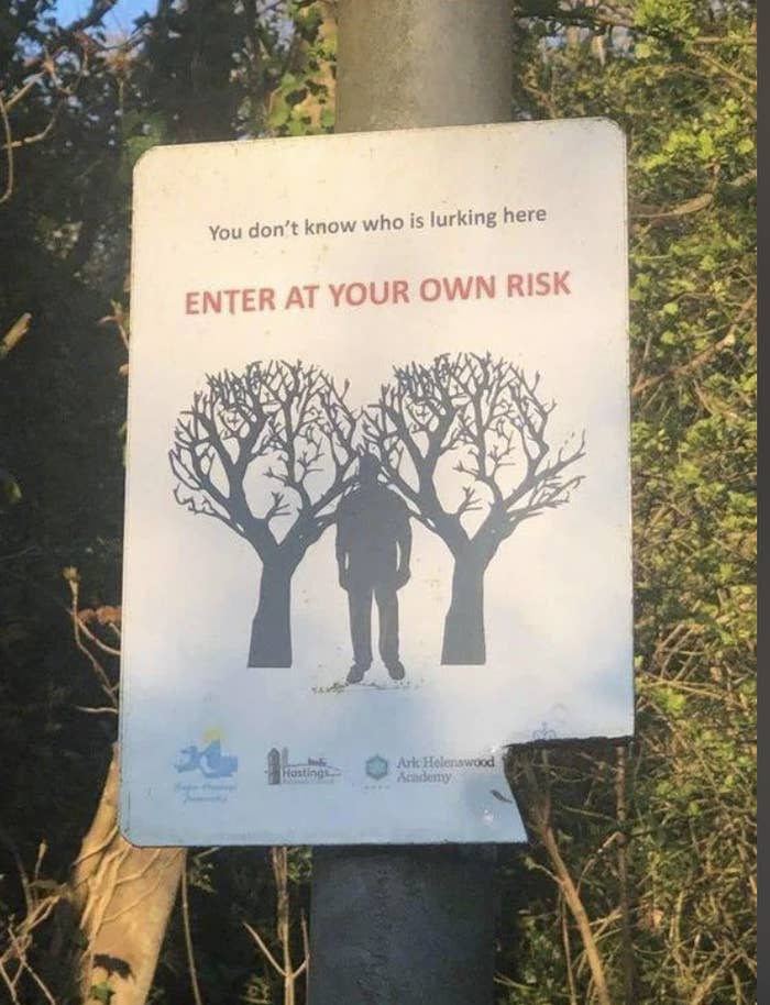 Warning sign with a silhouette between trees, text reads "Enter at your own risk," indicating a potentially unsafe area