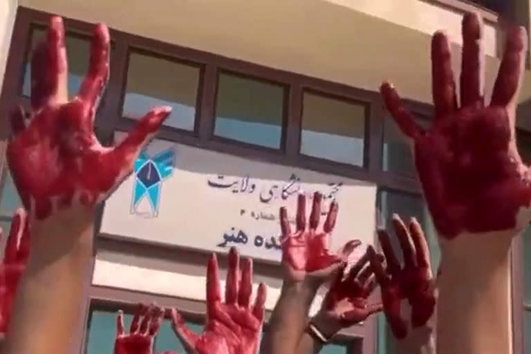 Esta imagen de un vídeo de la UGC publicado en Twitter el 9 de octubre de 2022 muestra a estudiantes iraníes de la Facultad de Artes de la Universidad Azad de Teherán participando en una protesta con las palmas de las manos cubiertas de pintura roja para simbolizar la sangre.