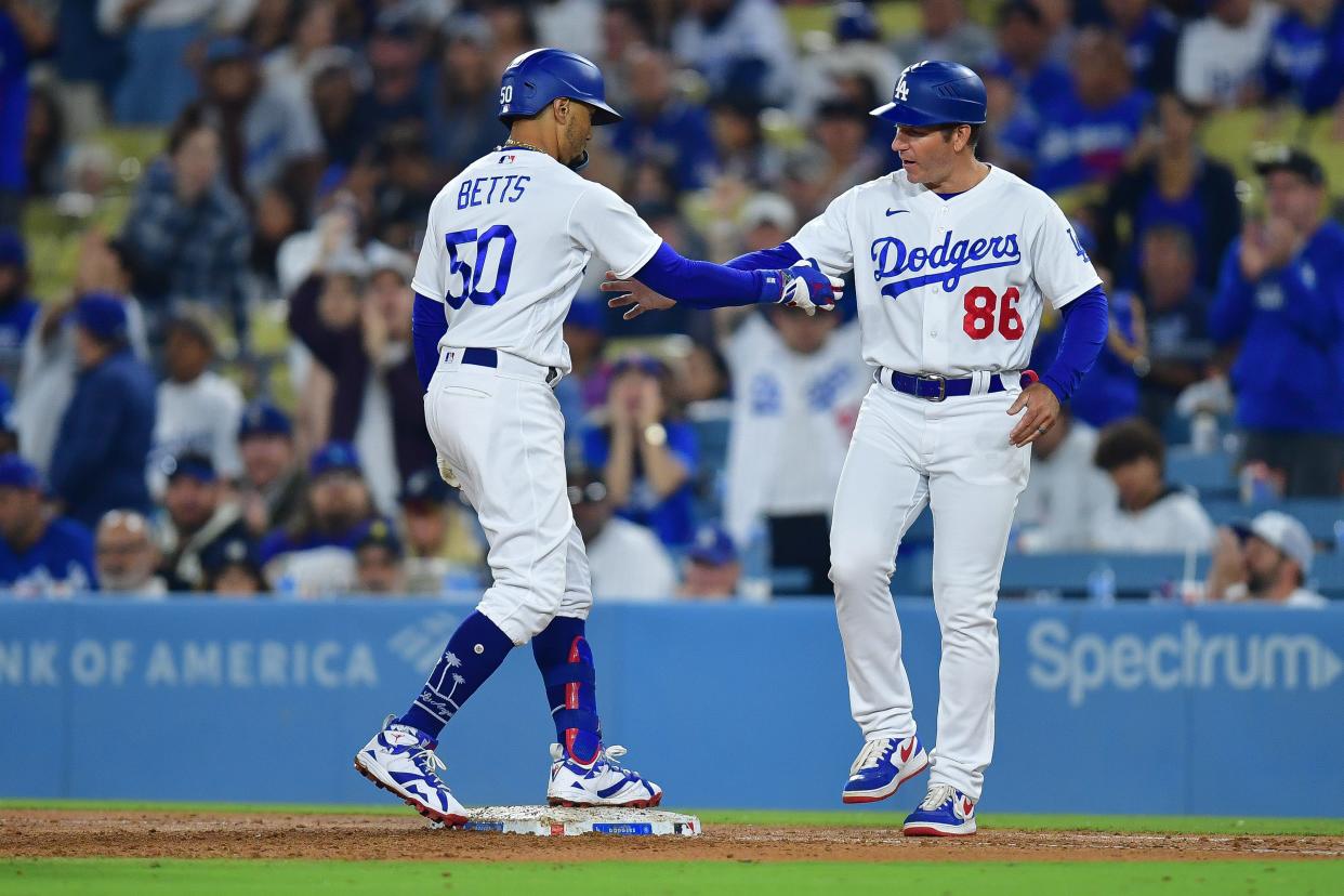 Los Angeles Dodgers second baseman Mookie Betts (50) is greeted by first base coach Clayton McCullough (86) after hitting a single against the Detroit Tigers during the seventh inning on Sept. 19, 2023, at Dodger Stadium.