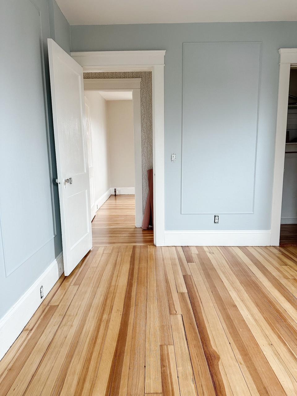 An empty room with a wood floor and light blue painted walls.