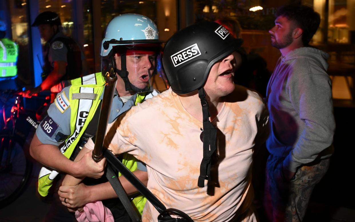 A man wearing a press helmet is taken into custody by police near the Israeli consulate in Chicago