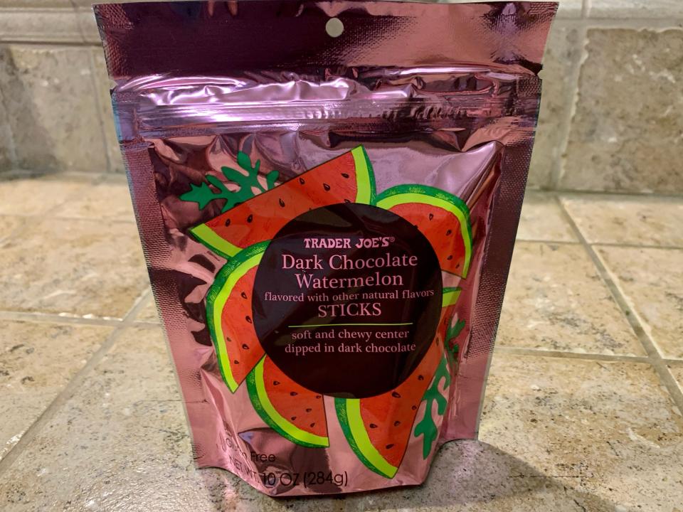 Trader joe's chocolate watermelon sticks in the original shiny pink packaging against beige tile