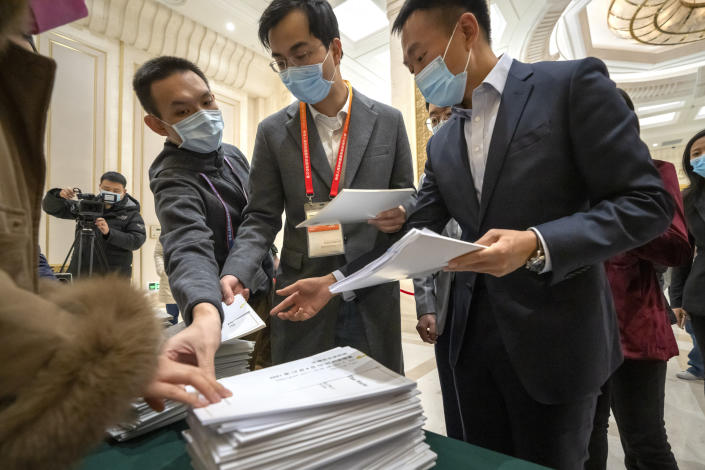 Journalists reach for copies of a Chinese government-produced report titled "Democracy that Works" before a press conference at the State Council Information Office in Beijing, Saturday, Dec. 4, 2021. China's Communist Party took American democracy to task on Saturday, sharply criticizing a global democracy summit being hosted by President Joe Biden next week and extolling the virtues of its governing system. (AP Photo/Mark Schiefelbein)