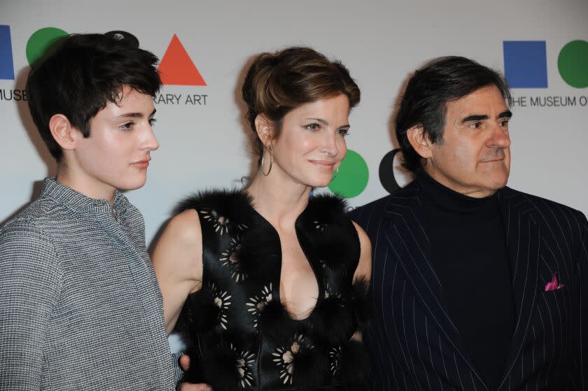 A boy, left, a woman and a man with brown hair posing together in formal attire