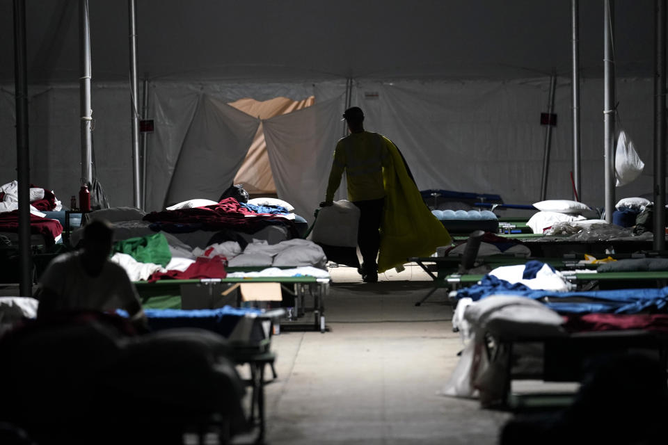 Electrical workers make their beds in a tent city in Amelia, La., Thursday, Sept. 16, 2021. In one massive white tent, hundreds of cots are spread out; experienced workers bring their own inflatable mattresses. Another tent houses a cafeteria that serves hot breakfast starting about 5 a.m., dinner and boxed lunches that can be eaten out in the field. (AP Photo/Gerald Herbert)