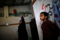 A Palestinian woman points to her house roof in Al-Shati refugee camp in Gaza City January 17, 2018. REUTERS/Mohammed Salem