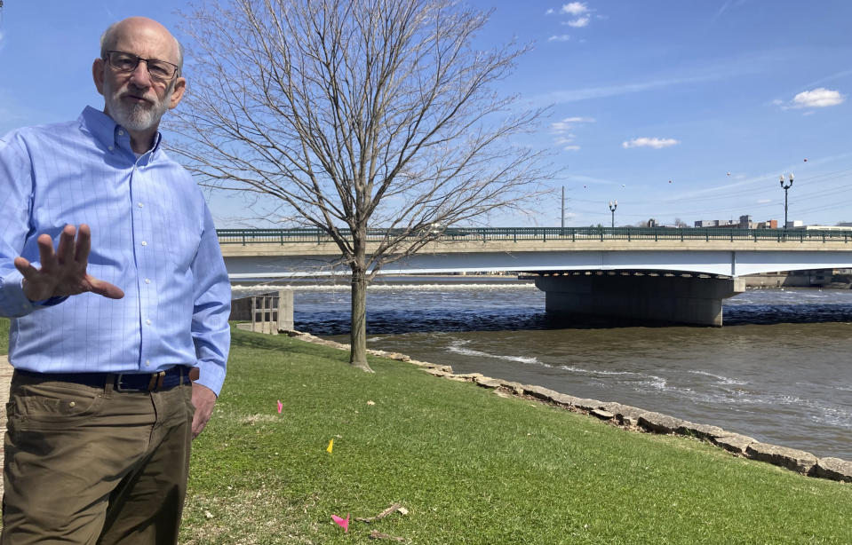 Tom Wadsworth gestures while standing on the bank of the Rock River in Dixon, Ill., on Tuesday, April 11, 2023, near the site of the May 4, 1873, baptismal ceremony, when a large crowd gathered on the Truesdell bridge before it toppled over, killing 46 and injuring 56 in the worst road-bridge disaster in American history. Wadsworth's great-grandmother, Gertie Wadsworth, was 3 1/2 years old and was in the arms of her grandmother, Christan Goble, the day the bridge collapsed. Goble died, but Gertie was plucked from the river downstream and revived. (AP Photo/John O'Connor)