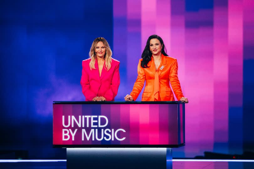 Malin Akerman and Petra Mede on the Eurovision stage stood above a United By Music board