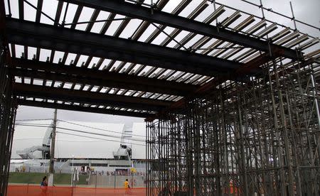 Workers work on areas of infrastructure in front of the construction site of the Arena das Dunas stadium, in Natal May 10, 2014. REUTERS/Nuno Guimaraes