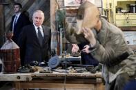 Russian President Vladimir Putin examines an exhibition depicting an armament repair shop at 3D panorama 'Memory speaks. The road through the war' in St.Petersburg