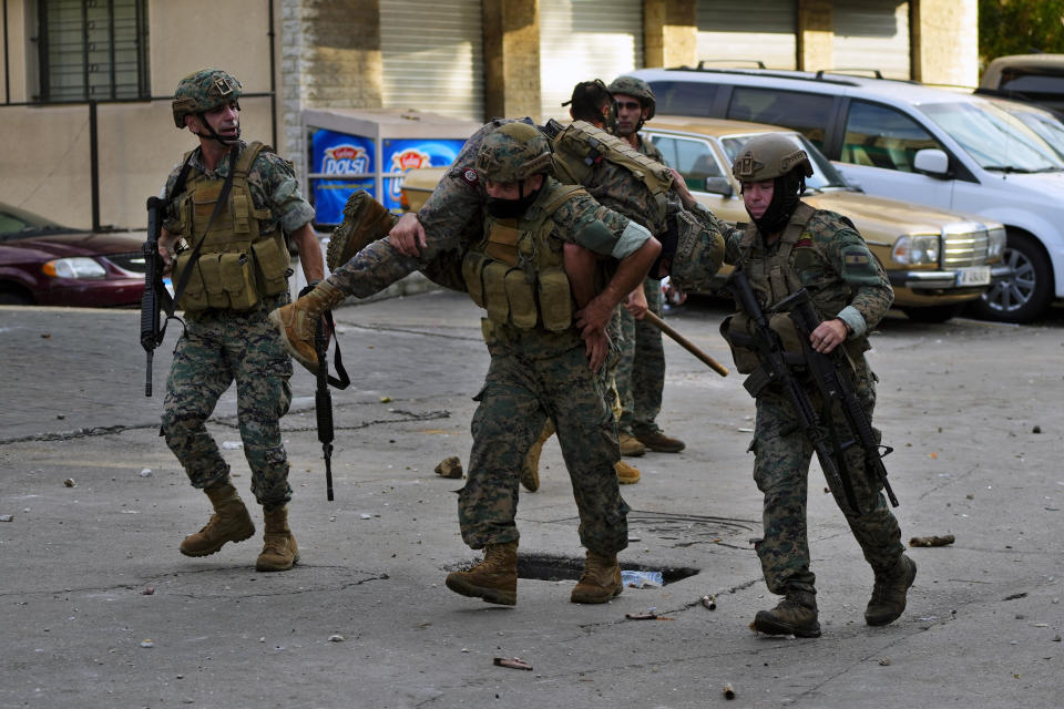 Lebanese army soldiers carry a wounded colleague who was injured during a demonstration, in solidarity with the Palestinian people in Gaza, near the U.S. embassy in Aukar, a northern suburb of Beirut, Lebanon, Wednesday, Oct. 18, 2023. Hundreds of angry protesters are clashing with Lebanese security forces in the Lebanese suburb Aukar near the United States Embassy. (AP Photo/Hassan Ammar)