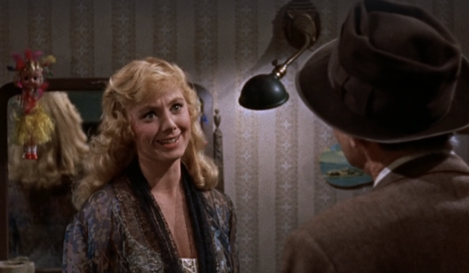 Woman smiling at a man in a hat, in a vintage indoor setting