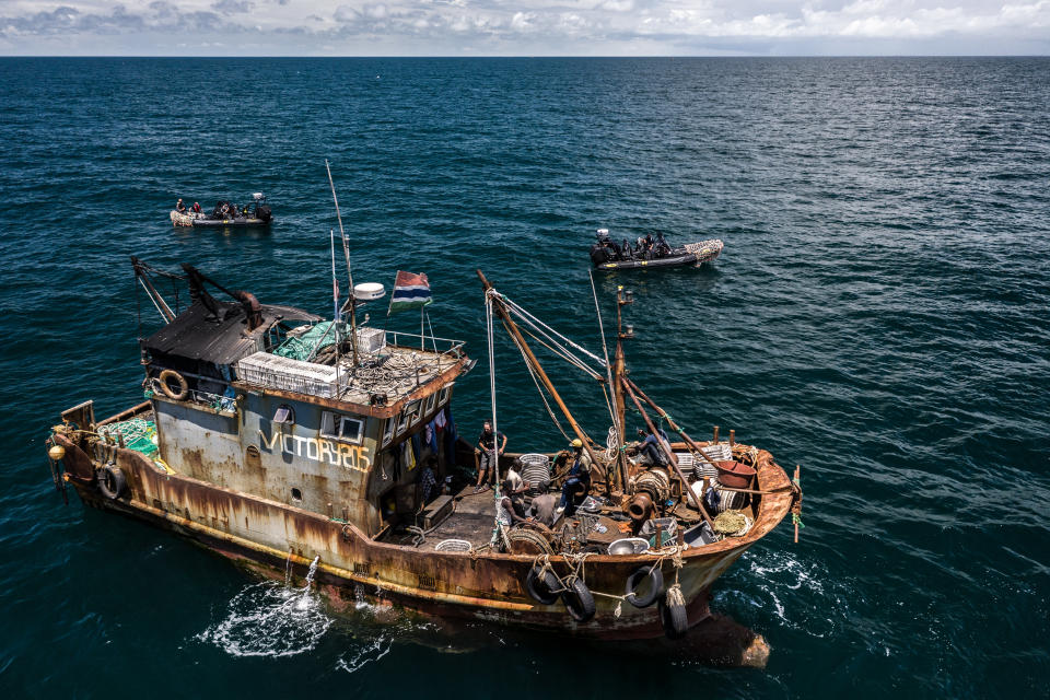 Rusty vessel Victory205 on the sea with two speedboats. (Fábio Nascimento/The Outlaw Ocean Project, Gambia, 2019)