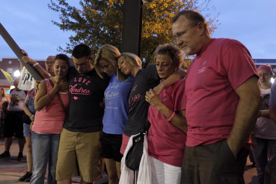 Friends and family of Andrea Vellinga, of Pendleton, Ind., bow their heads during a moment of silence for the seven people killed and dozens injured a year ago when stage rigging collapsed at the Indiana State Fair in Indianapolis, Monday, Aug. 13, 2012. Vellinga was injured in the stage collapse. (AP Photo/Michael Conroy)