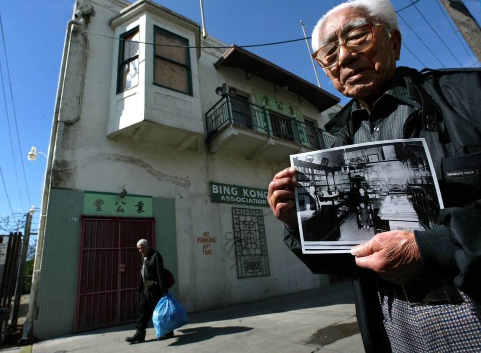 Nori Masuda, 88, shows a photograph taken in 1921 of the interior of the Masuda Bookstore owned by his parents, at 921 China Alley, background left, (where the red grated door is) in this file photo from 2005. (In the photo: his father Matichiro Masuda, left, his mother Tasu, center, his sister Dorothy, front center.)