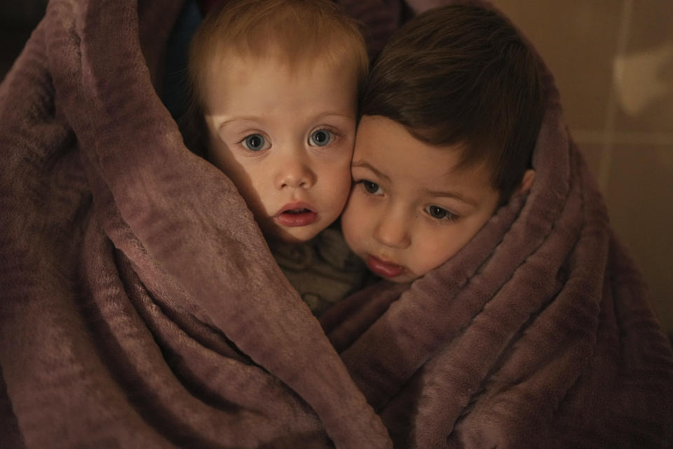 The children of medical workers warm themselves in a blanket as they wait for their relatives in a hospital in Mariupol, Ukraine, Friday, March 4, 2022. (AP Photo/Evgeniy Maloletka)