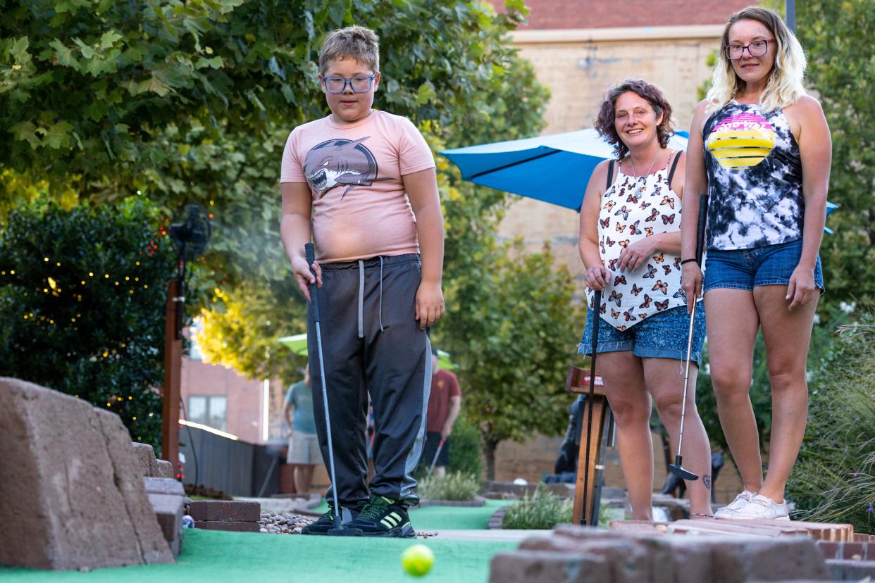 Zachary Unruh, left, Janelle McMichael-Puller, center, and Laura Bond, right, play at the Brickopolis miniature golf course.