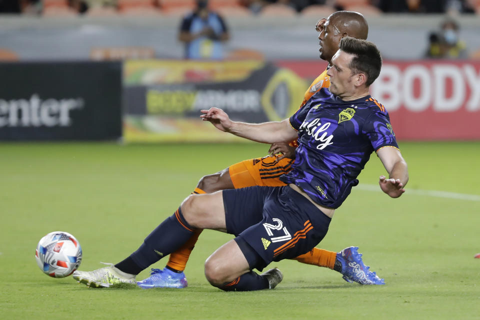 Houston Dynamo midfielder Fafa Picault, back, attempts a shot on goal as Seattle Sounders defender Shane O'Neill (27) blocks the kick during the first half of an MLS soccer match Saturday, Oct. 16, 2021, in Houston. (AP Photo/Michael Wyke)