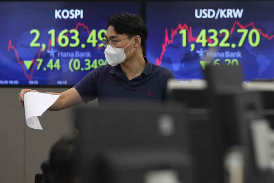 A currency trader gestures in front of the screens showing the Korea Composite Stock Price Index (KOSPI), left, and the exchange rate of South Korean won against the U.S. dollar, at the foreign exchange dealing room of the KEB Hana Bank headquarters in Seoul, South Korea, Friday, Sept. 30, 2022. Asian stocks have sunk again after German inflation spiked higher, British Prime Minister Liz Truss defended a tax-cut plan that rattled investors and Chinese manufacturing weakened. (AP Photo/Ahn Young-joon)
