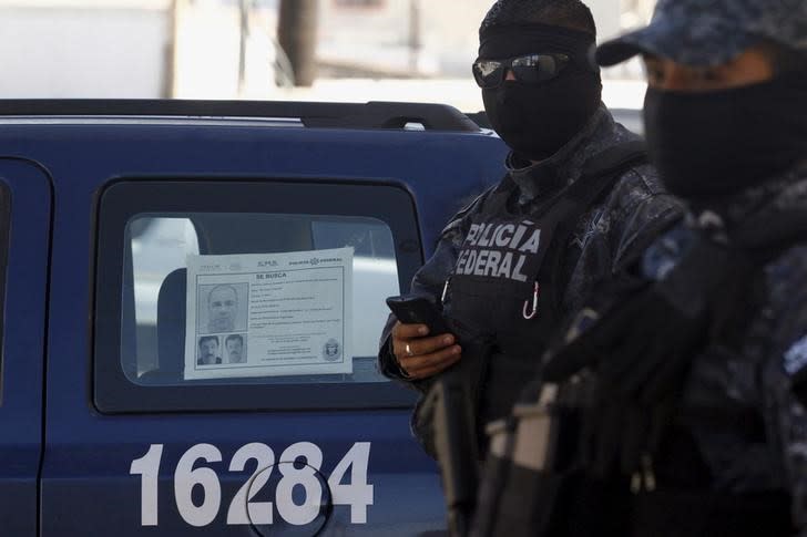 Federal police officers stand guard near a vehicle with a 