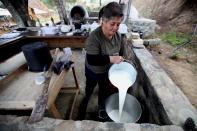 In this photo taken Wednesday Dec. 11, 2019, Aphrodite Philippou, 73, throws the milk in a saucepan to makes Cyprus' halloumi cheese at a farm in Kampia village near Nicosia, Cyprus. Cyprus' halloumi cheese, with a tradition dating back some five centuries, is the island nation's leading export. It's goat and sheep milk content makes it a hit with health-conscious cheese lovers in Europe and beyond. It's added appeal is that unlike other cheeses, it doesn't melt when heated up. (AP Photo/Petros Karadjias)