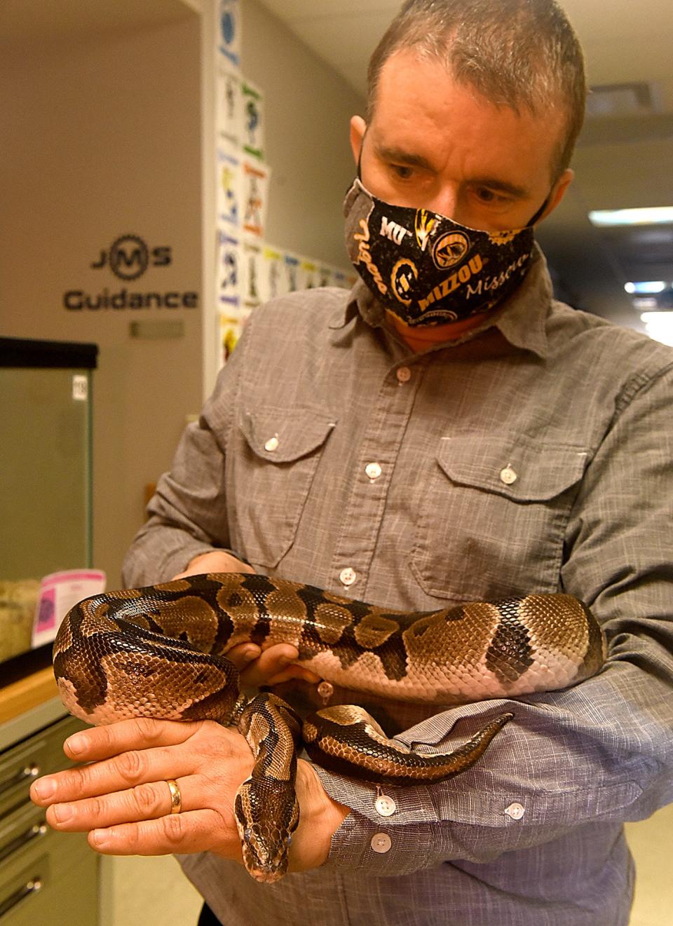 Mike Szydlowski, K-12 science coordinator, handles Cleo, a ball python that is part of the Jefferson Middle School Zoo, on Friday during the morning feeding of the animals.