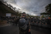 Guatemalan soldiers block the road where Honduran migrants, hoping to reach the U.S. border, rest on the side of a highway in Vado Hondo, Guatemala, Saturday, Jan. 16, 2021. Guatemalan authorities estimated that as many as 9,000 Honduran migrants crossed into Guatemala as part of an effort to form a new caravan to reach the U.S. border. (AP Photo/Sandra Sebastian)