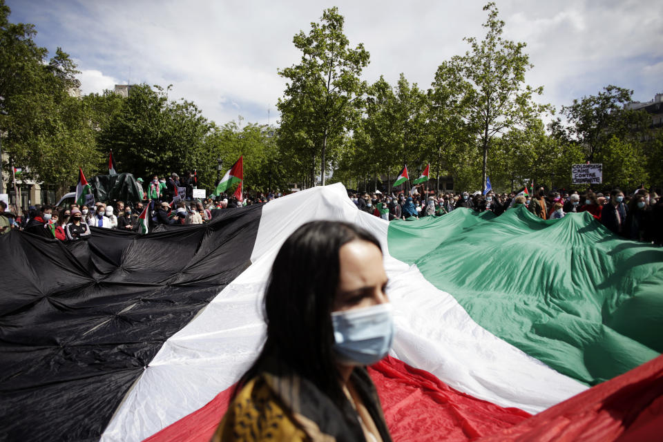 Protesters hold a giant Palestinian flag in Paris, Saturday, May 22, 2021, as they take part in a rally supporting Palestinians. Egyptian mediators held talks Saturday to firm up an Israel-Hamas cease-fire as Palestinians in the Hamas-ruled Gaza Strip began to assess the damage from 11 days of intense Israeli bombardment.Supporters of the Palestinians. (AP Photo/Thibault Camus)