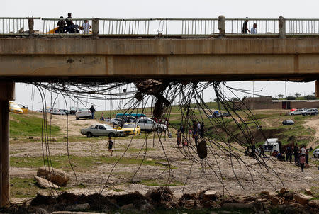 A ruined bridge is seen as Iraqi families and youths enjoy their Friday holiday at Shallalat district (Arabic for "waterfalls") in eastern Mosul, Iraq, April 21, 2017. REUTERS/ Muhammad Hamed