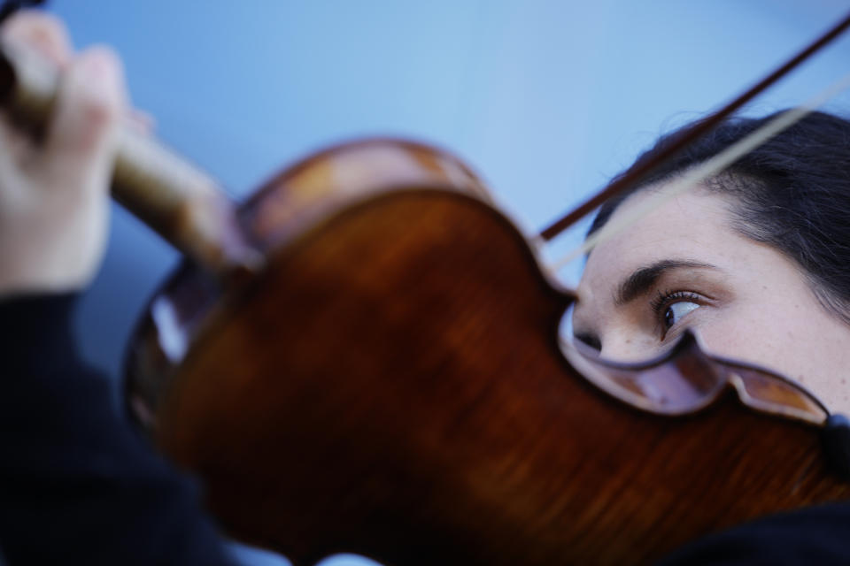 A striking musician of the Paris Opera house performs outside the Bastille Opera house Tuesday, Dec. 31, 2019 in Paris. (AP Photo/Kamil Zihnioglu)