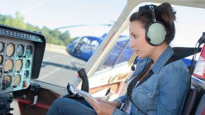 helicopter pilot reading a manual while sitting in cockpit