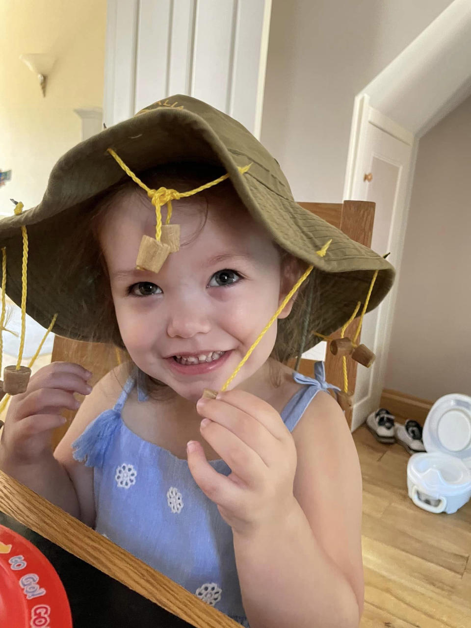 Raeyah before feeling growing pains and falling ill wearing a hat with corks handing from it. 