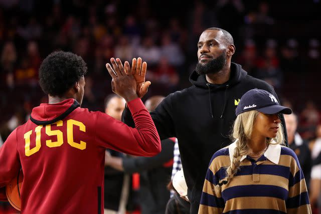 <p>Meg Oliphant/Getty </p> Bronny James #6 of the USC Trojans greets his dad, LeBron James of the Los Angeles Lakers