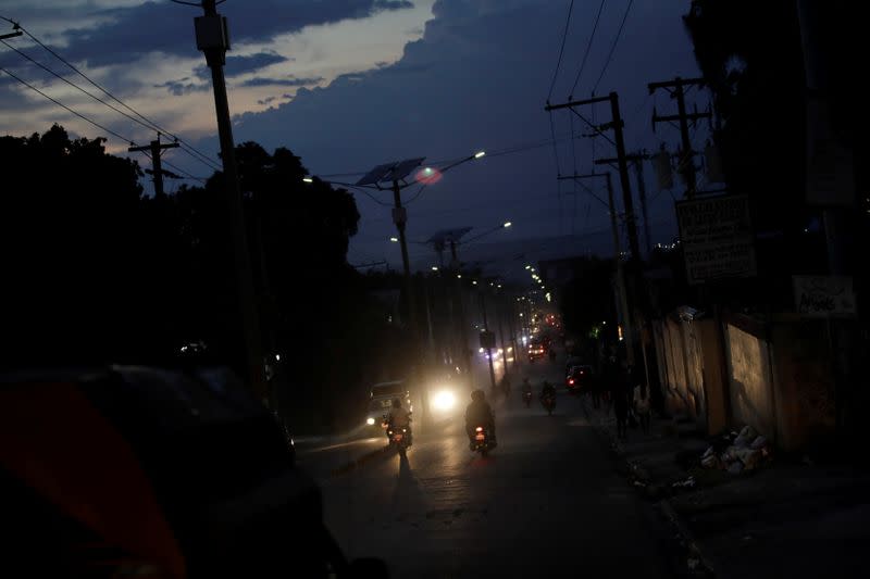 Vehicles drive along Delmas road at dusk in Port-au-Prince