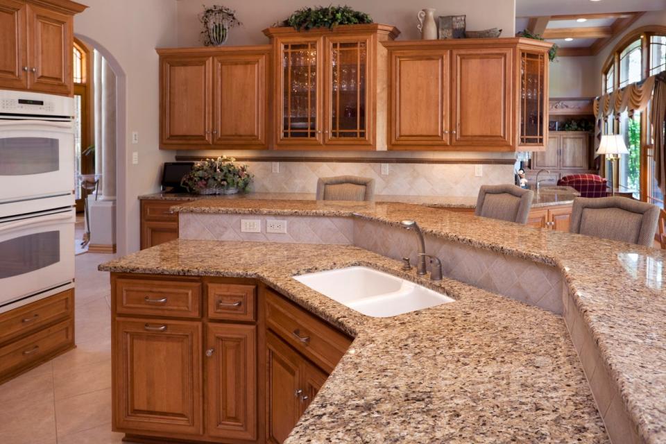 Traditional kitchen with brown wood cabinets and a two-level brown granite countertop.