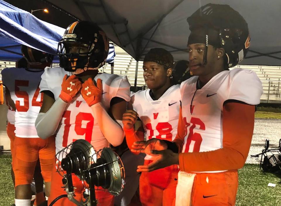 Members of the Vance Cougars football team huddle under a tent with portable heaters during their 27-7 win over Mallard Creek Friday night.